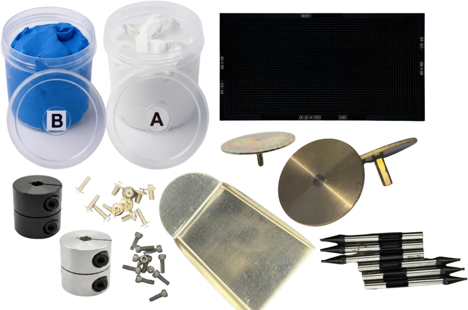 Semsons Tech consumables and spares laid out together: two-part silicone setting putty in labelled A and B tubs, a perforated setting plate, a brass-framed setting tray, brass and plated mounting discs, two clamp shaft couplings, assorted machine screws and six suction nozzles.